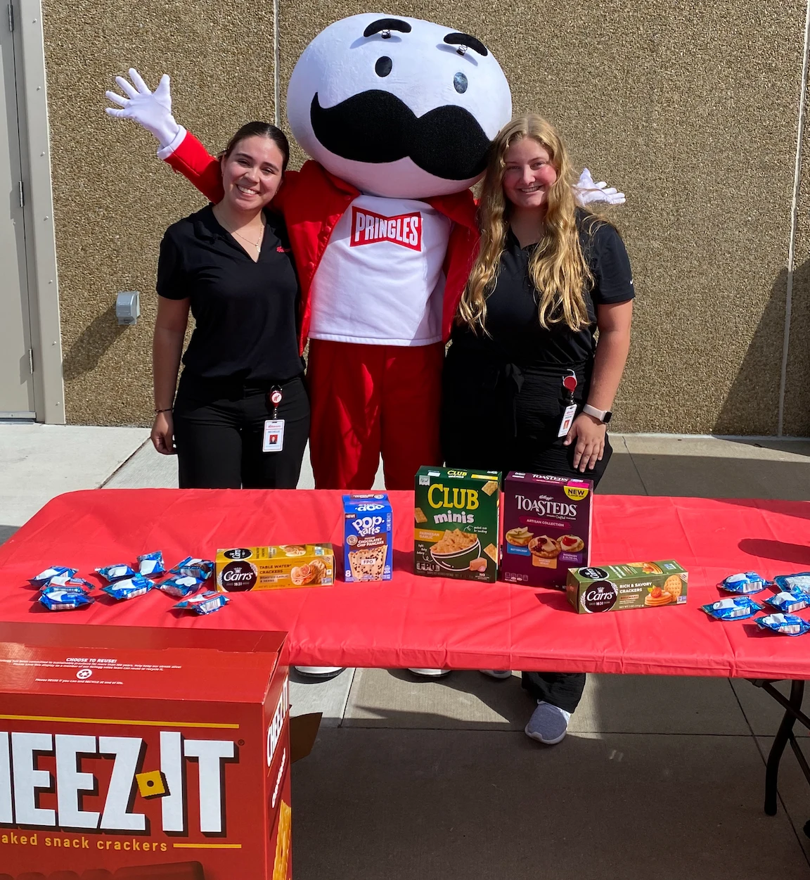 Kellanova employee Madeline Kastel with Pringles mascot and table of Kellanova products